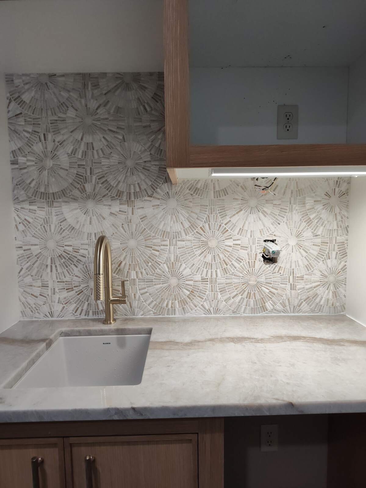 Patterned tile backsplash finished cleanly along a stone countertop and sink