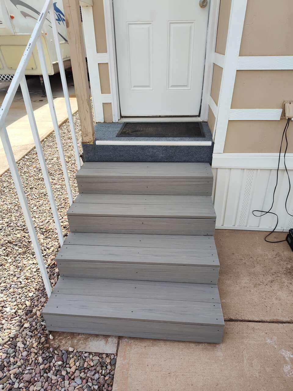 Rebuilt entry steps with gray composite treads and a new landing at a home's side door