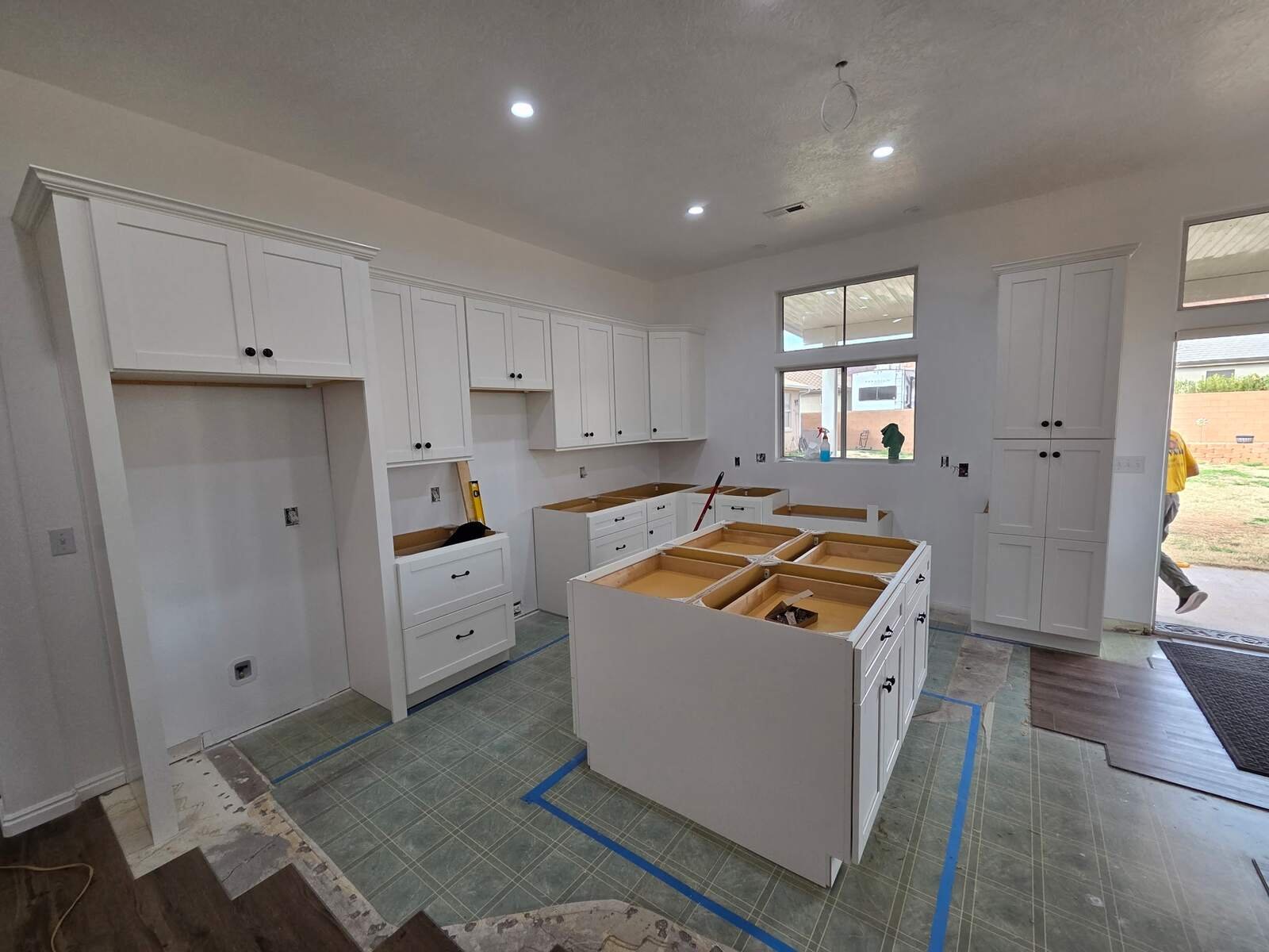 Kitchen remodel in progress with new white cabinets, pantry towers and island being installed
