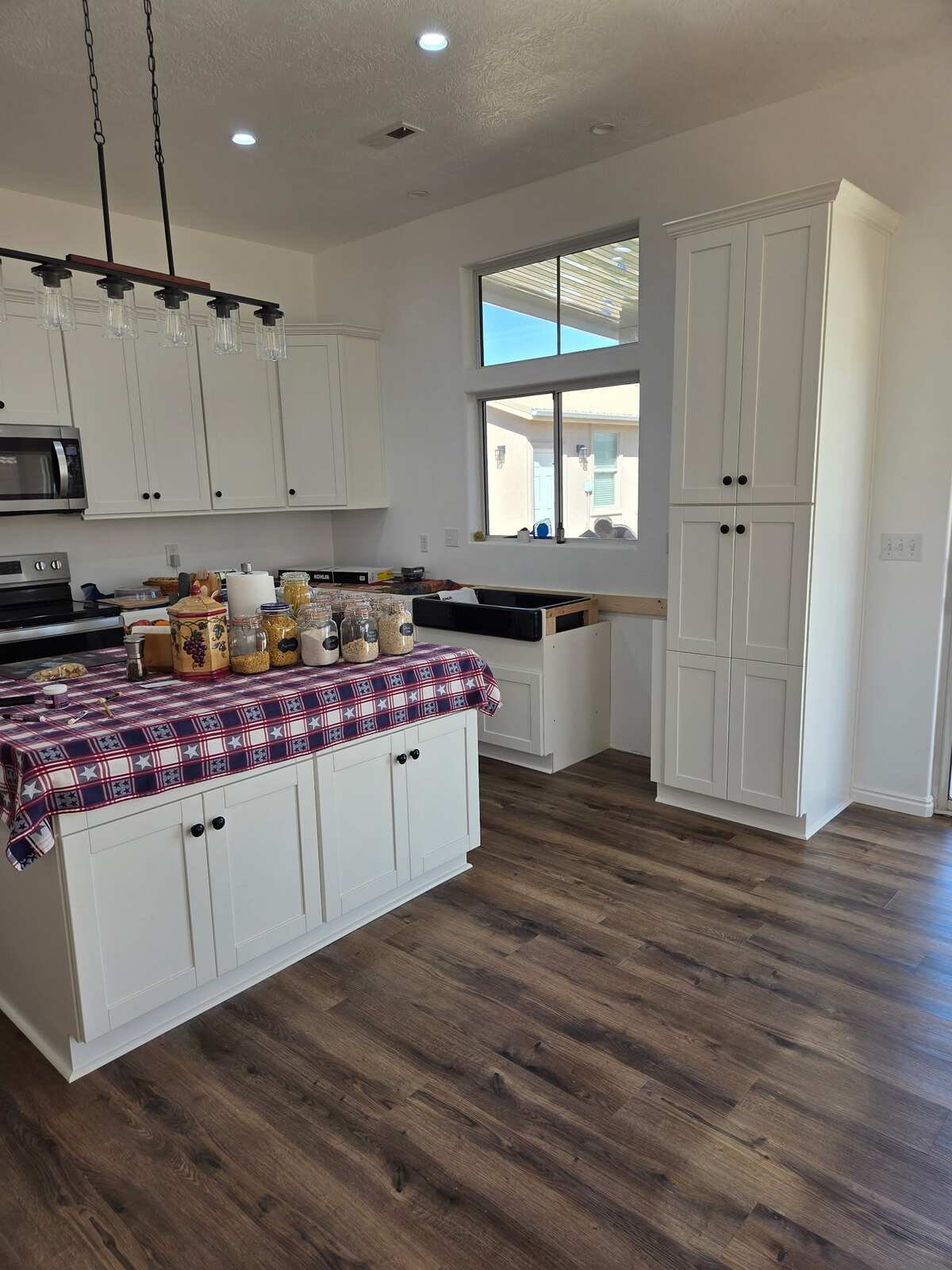 Remodeled kitchen with white shaker cabinets, a new island and wood-look plank flooring