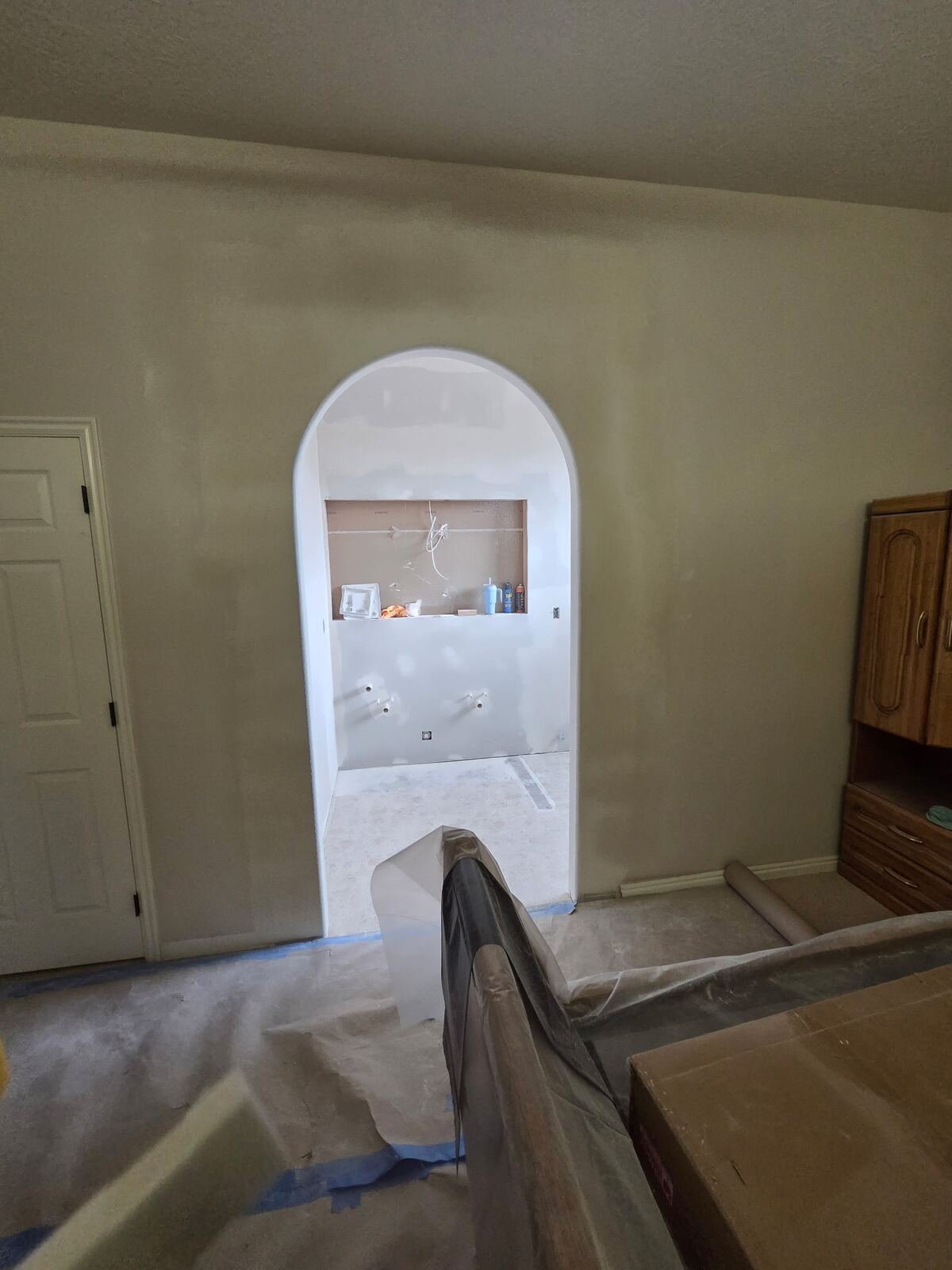 Arched doorway with fresh drywall mud during a primary bathroom renovation